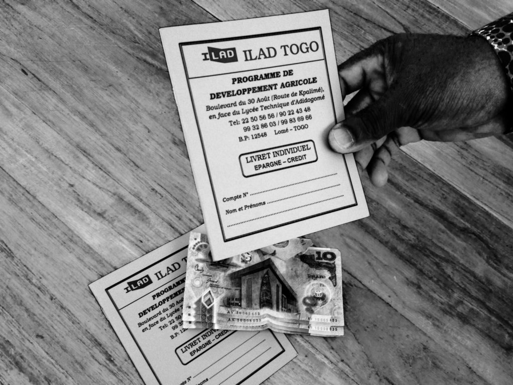 ILAD Togo Programe Development Agriculture card (in French) being held. Money on table with another card.