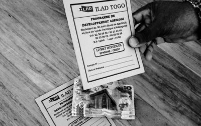 ILAD Togo Programe Development Agriculture card (in French) being held. Money on table with another card.
